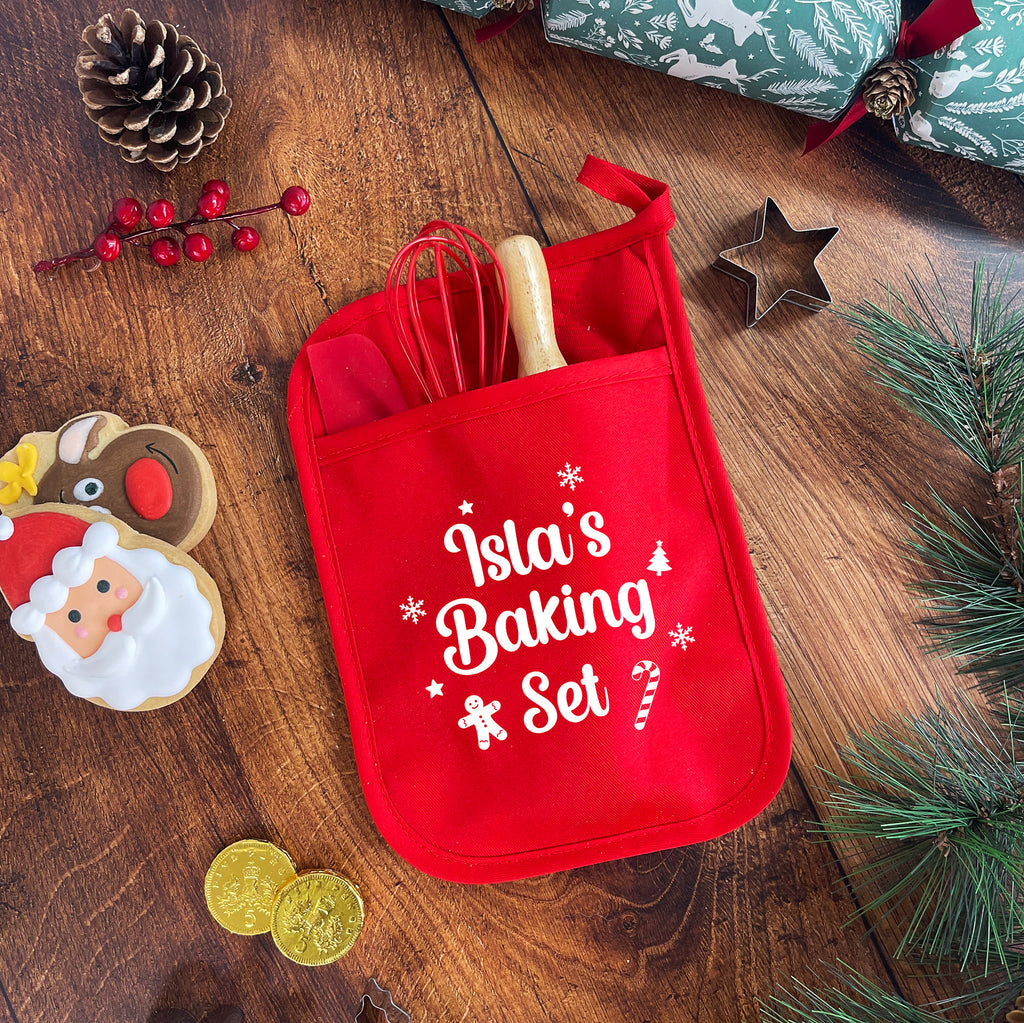 Red baking set pouch with 'Isla's Baking Set' text on a wooden surface with Christmas decorations.