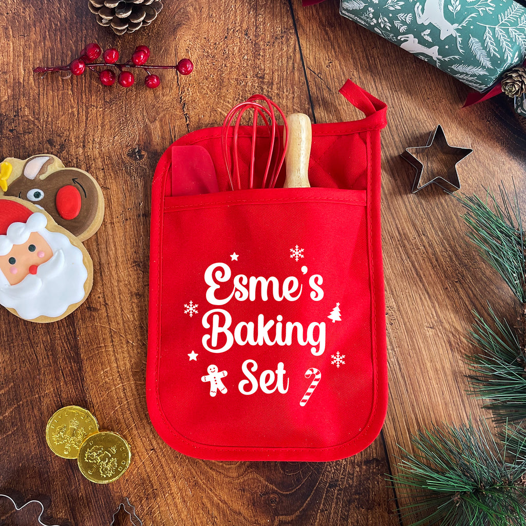 Red baking set with utensils on a wooden surface with Christmas decorations.